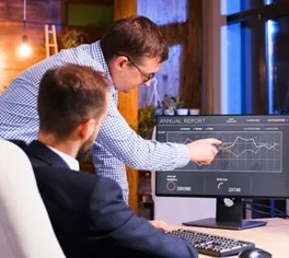 Zwei Männer analysieren Finanzdaten auf einem Computerbildschirm. Für BPA BPO