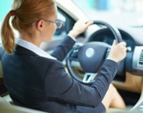 Frau in Anzug im Auto sitzend. Für ISO 21434